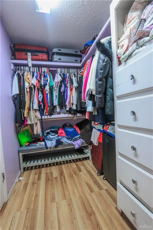 walk in closet with light hardwood / wood-style flooring