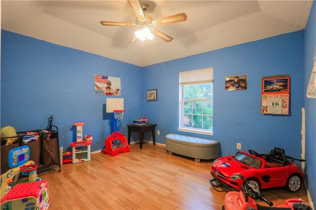 playroom featuring a textured ceiling, light hardwood / wood-style floors, ceiling fan, and lofted ceiling