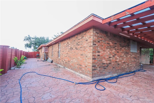 view of property exterior featuring a pergola and a patio