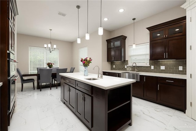 kitchen featuring marble finish floor, a sink, tasteful backsplash, and light countertops