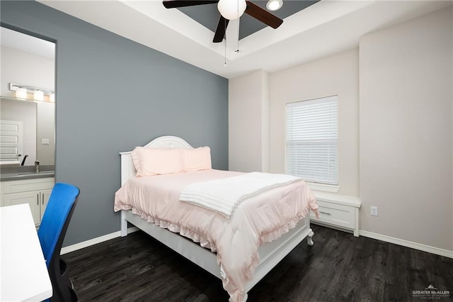 bedroom with dark wood-style floors, baseboards, ceiling fan, and a tray ceiling