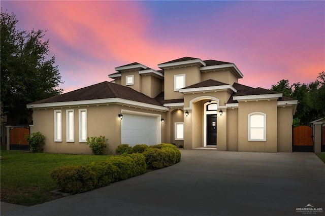 view of front facade featuring a front lawn, a garage, a gate, driveway, and stucco siding