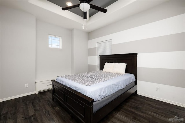 bedroom with dark wood-style floors, ceiling fan, a raised ceiling, and baseboards