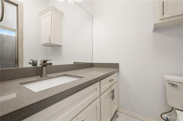 bathroom featuring toilet, vanity, marble finish floor, and baseboards