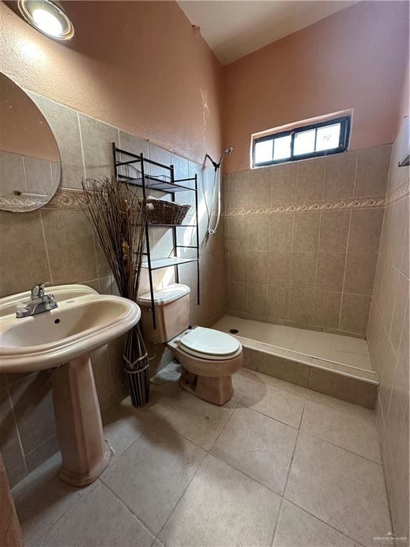 bathroom featuring tile patterned flooring, toilet, tile walls, and a tile shower