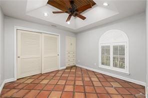 unfurnished bedroom featuring recessed lighting, a closet, a raised ceiling, and baseboards