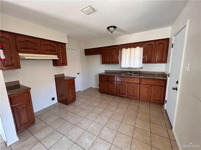 kitchen with dark countertops, light tile patterned flooring, visible vents, and a sink