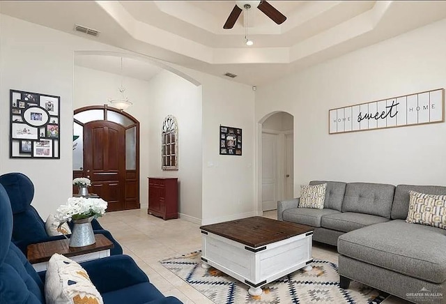 living area featuring visible vents, arched walkways, a raised ceiling, and ceiling fan