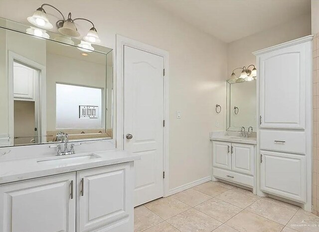 bathroom with baseboards, a sink, two vanities, and tile patterned floors