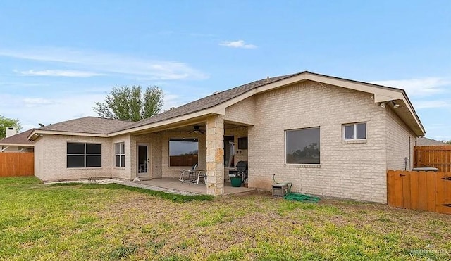 rear view of house with brick siding, a patio area, fence, and a lawn