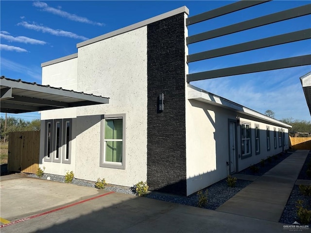 view of side of home with a patio area, fence, and stucco siding