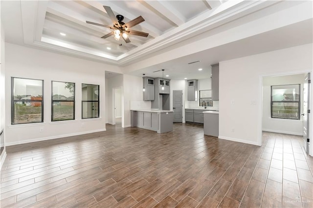 unfurnished living room with plenty of natural light, ceiling fan, dark hardwood / wood-style flooring, and sink