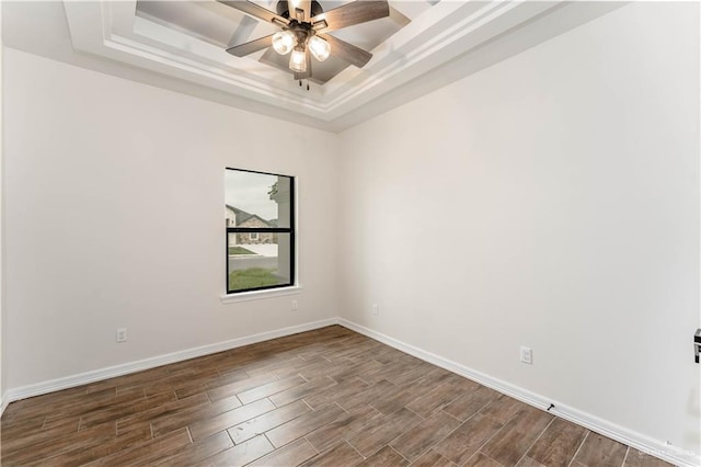 spare room featuring a raised ceiling, ceiling fan, and wood-type flooring