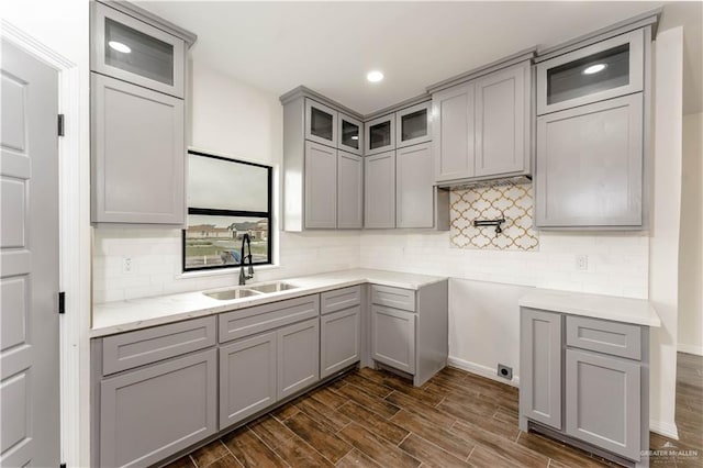 kitchen with gray cabinetry, backsplash, sink, and dark wood-type flooring