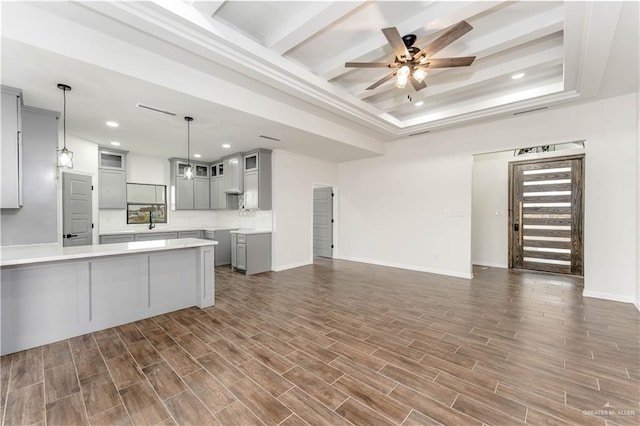 kitchen with a tray ceiling, ceiling fan, dark wood-type flooring, gray cabinets, and hanging light fixtures