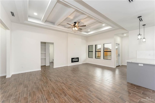 unfurnished living room featuring ceiling fan, a raised ceiling, and dark wood-type flooring