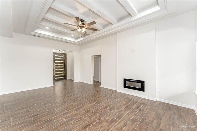 unfurnished living room with a raised ceiling, ceiling fan, and dark wood-type flooring