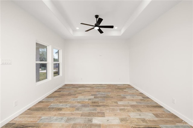 spare room with light hardwood / wood-style flooring, a raised ceiling, and ceiling fan