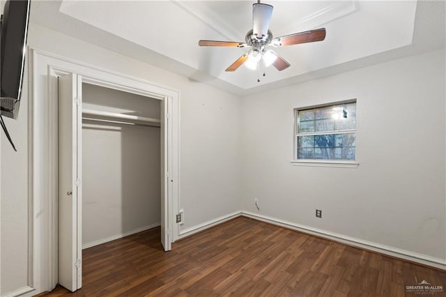 unfurnished bedroom featuring ceiling fan, dark hardwood / wood-style floors, a raised ceiling, and a closet