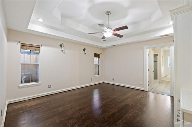 empty room with ceiling fan, light hardwood / wood-style flooring, and a tray ceiling