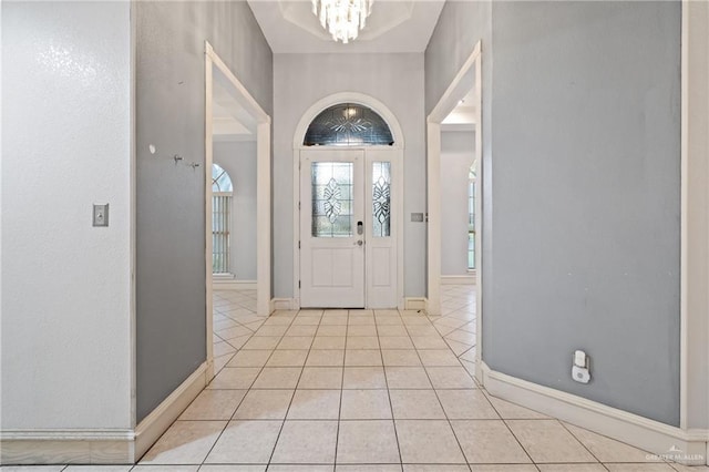 tiled foyer entrance with an inviting chandelier