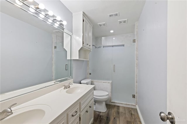 bathroom featuring hardwood / wood-style floors, vanity, toilet, and walk in shower