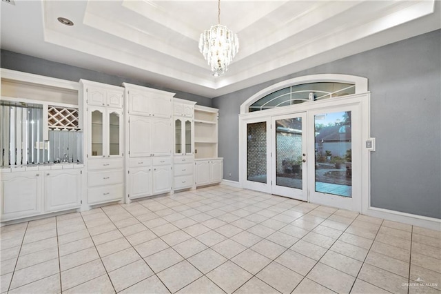 unfurnished dining area featuring a chandelier, light tile patterned floors, and a tray ceiling