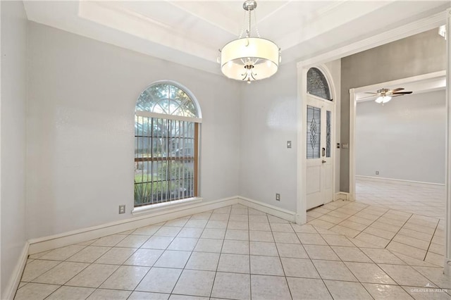 tiled empty room featuring a tray ceiling and ceiling fan