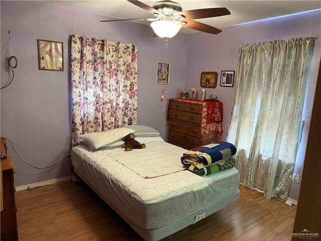 bedroom with a ceiling fan, baseboards, and wood finished floors