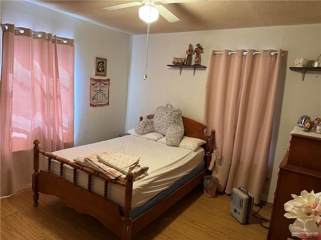 bedroom featuring a textured ceiling, wood finished floors, and a ceiling fan