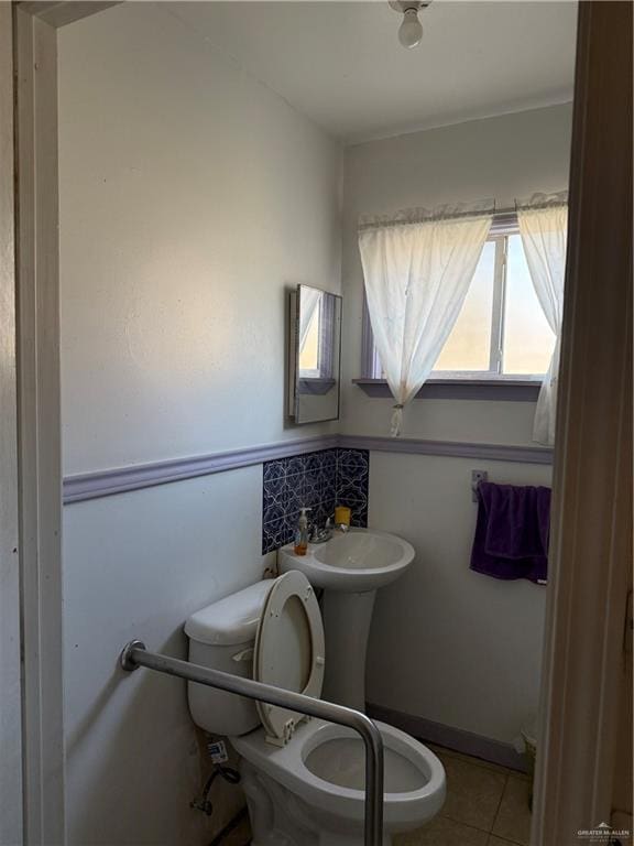 half bathroom featuring tile patterned flooring and toilet