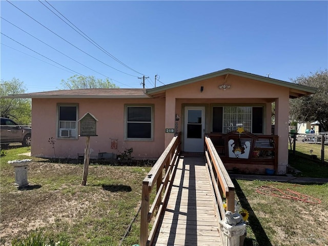 view of front of property featuring covered porch, stucco siding, a front lawn, and fence