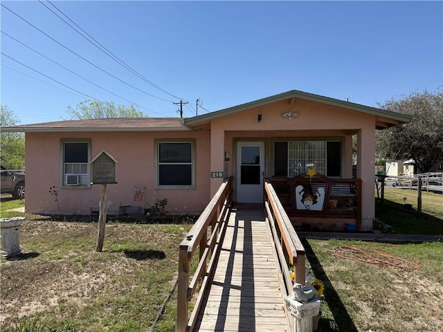 view of front of property featuring stucco siding, covered porch, and a front lawn