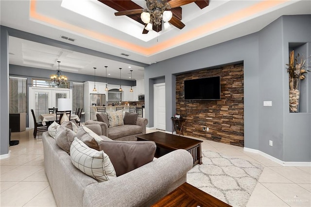 living room featuring a raised ceiling, french doors, light tile patterned floors, and ceiling fan with notable chandelier