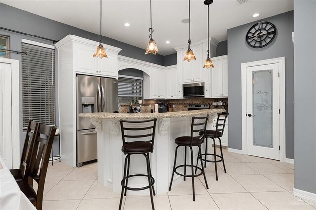 kitchen featuring pendant lighting, a center island with sink, white cabinetry, and stainless steel appliances