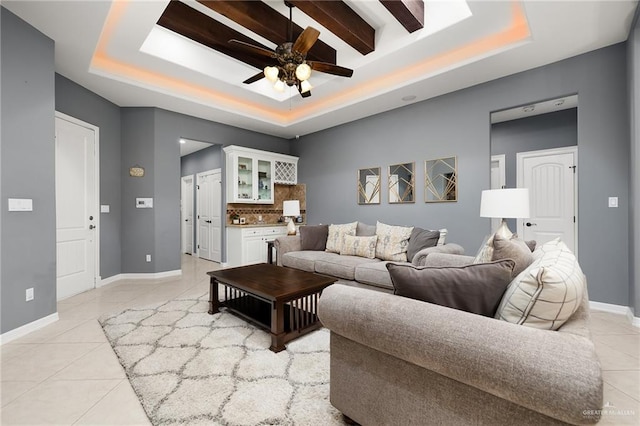 tiled living room featuring ceiling fan and a raised ceiling