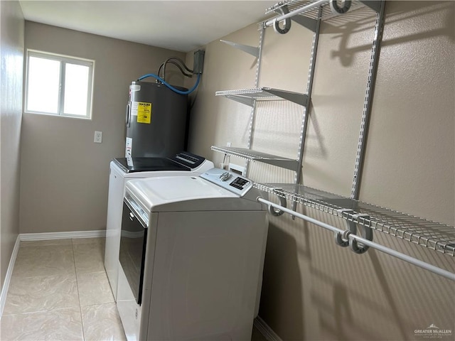 washroom featuring washing machine and dryer, laundry area, water heater, and baseboards