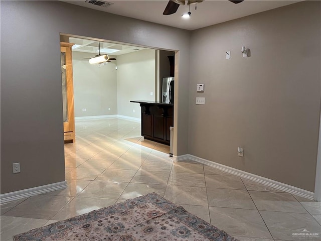 unfurnished room with visible vents, light tile patterned floors, a ceiling fan, and baseboards