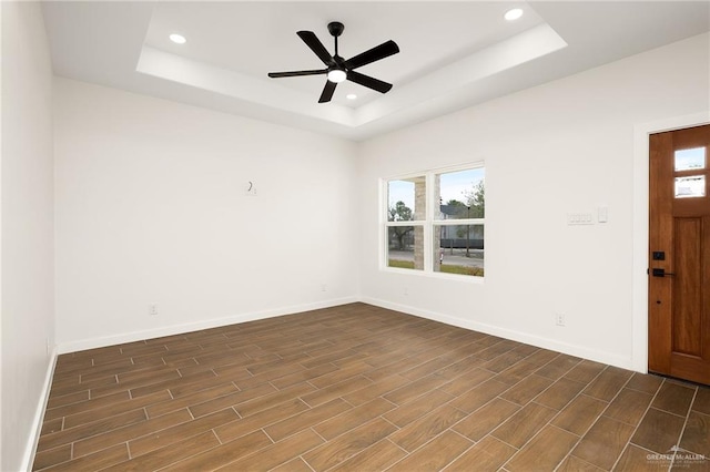 unfurnished room with dark hardwood / wood-style flooring, a tray ceiling, and ceiling fan