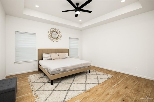 bedroom featuring baseboards, recessed lighting, a ceiling fan, a raised ceiling, and wood finished floors