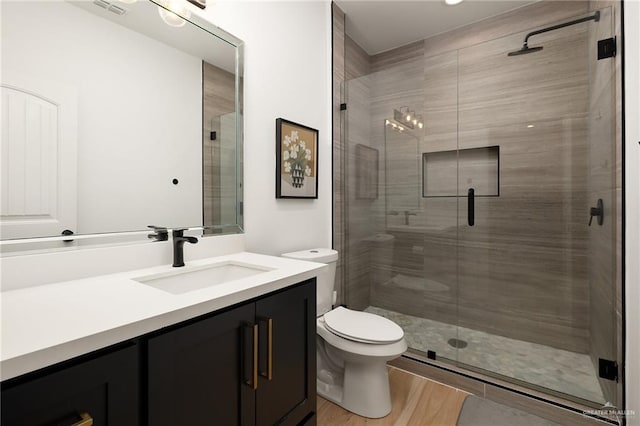 full bath with toilet, a stall shower, wood finished floors, and vanity