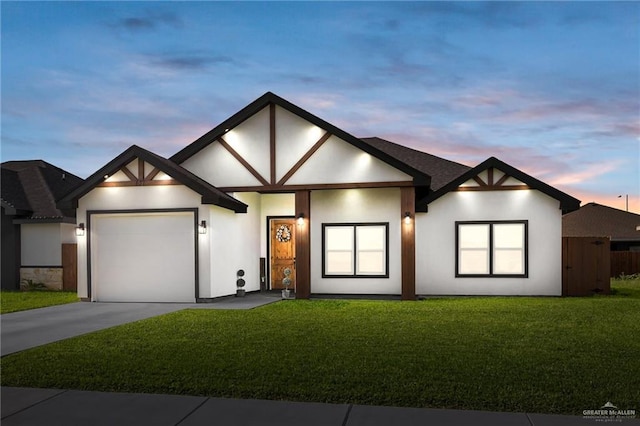 view of front of home featuring concrete driveway, stucco siding, an attached garage, and a lawn