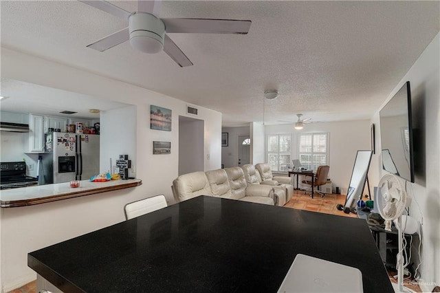 interior space featuring a textured ceiling, visible vents, and a ceiling fan