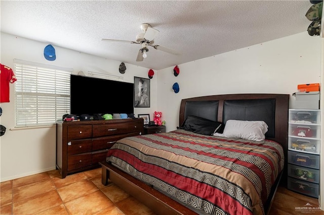 bedroom featuring tile patterned flooring, baseboards, ceiling fan, and a textured ceiling