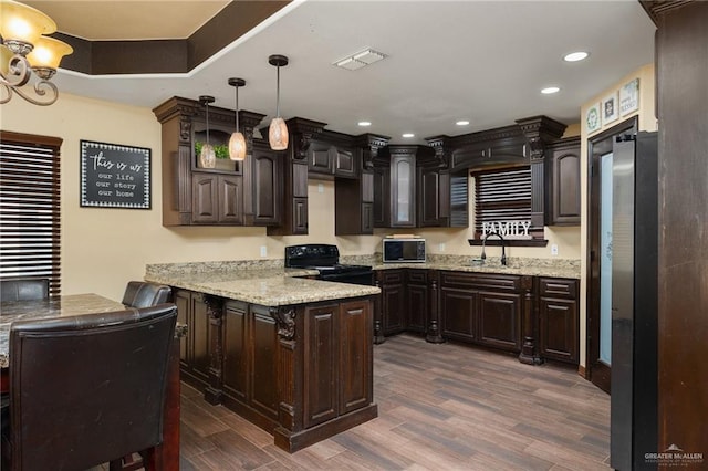 kitchen featuring black stove, dark brown cabinets, sink, dark hardwood / wood-style floors, and hanging light fixtures