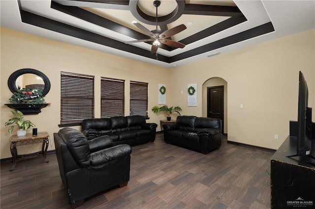 living room featuring dark hardwood / wood-style flooring, ceiling fan, and a raised ceiling