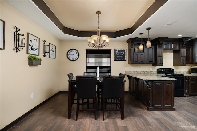 dining space featuring a raised ceiling, dark hardwood / wood-style flooring, and a notable chandelier