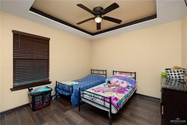 bedroom featuring ceiling fan, dark hardwood / wood-style flooring, and a raised ceiling