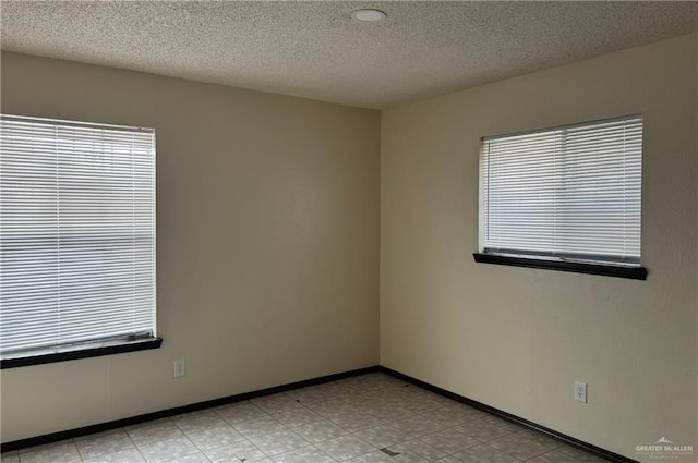 empty room with plenty of natural light and a textured ceiling