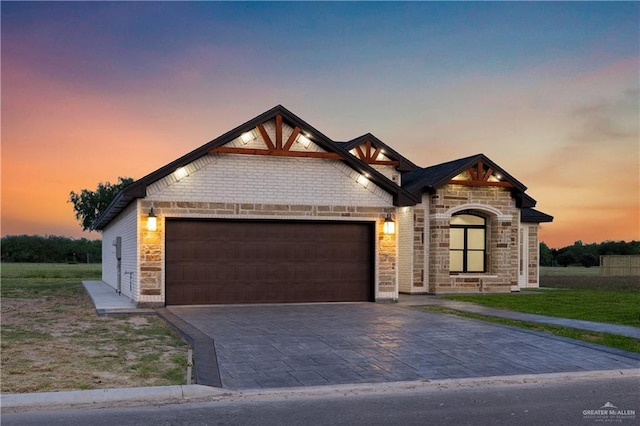 view of front of house featuring a lawn, an attached garage, decorative driveway, and stone siding